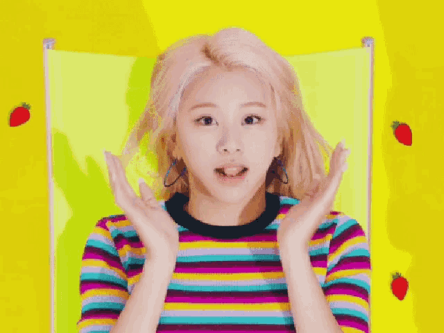 a woman wearing a colorful striped shirt is sitting in front of strawberries