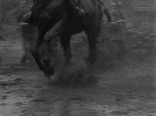 a black and white photo of a person riding a horse in the rain