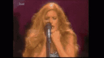a woman with long blonde hair is singing into a microphone .