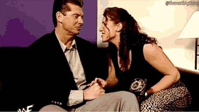 a man and a woman are sitting on a couch and holding hands