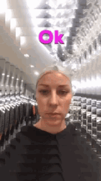 a woman in a black dress stands in front of a mirror with the word ok above her head