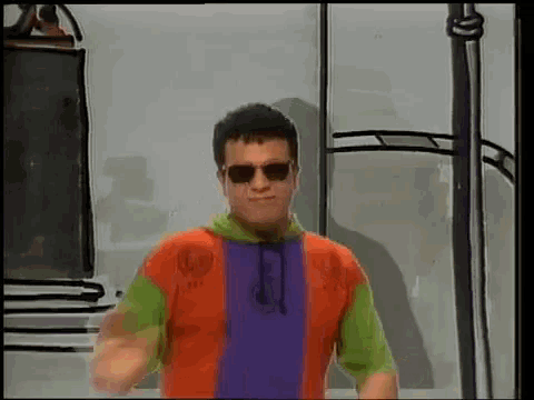 a man wearing sunglasses and a colorful shirt stands in a room