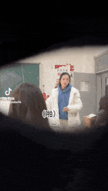 a woman is standing in a classroom with other people .