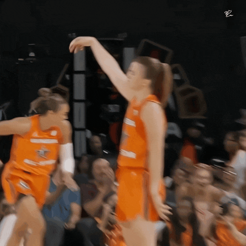 a blurry picture of two female basketball players wearing orange uniforms with the letters bz on the bottom