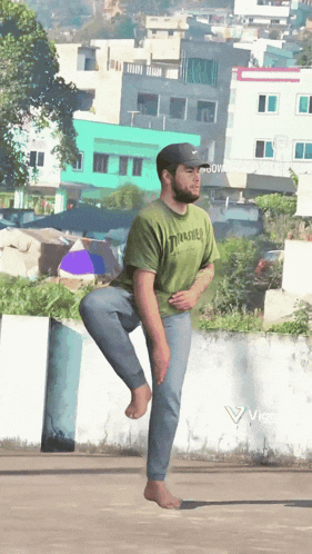 a man wearing a green thrasher shirt stands on one leg