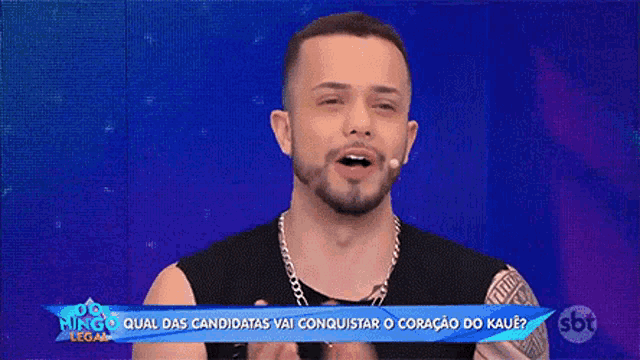 a man with a beard is talking into a microphone on a television show