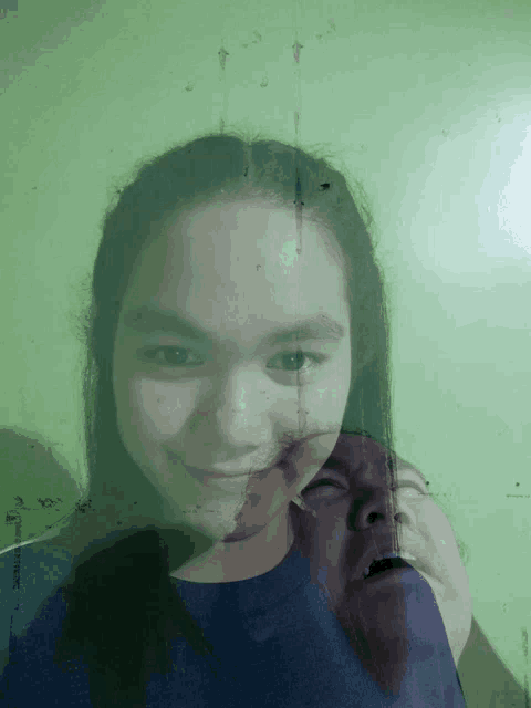 a girl 's face is partially obscured by a reflection of another person 's face