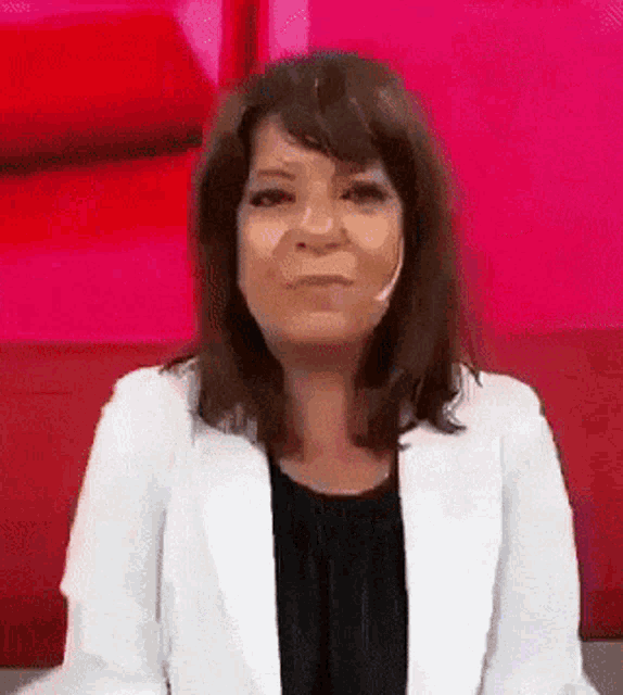 a woman wearing a white jacket and a black top is making a funny face