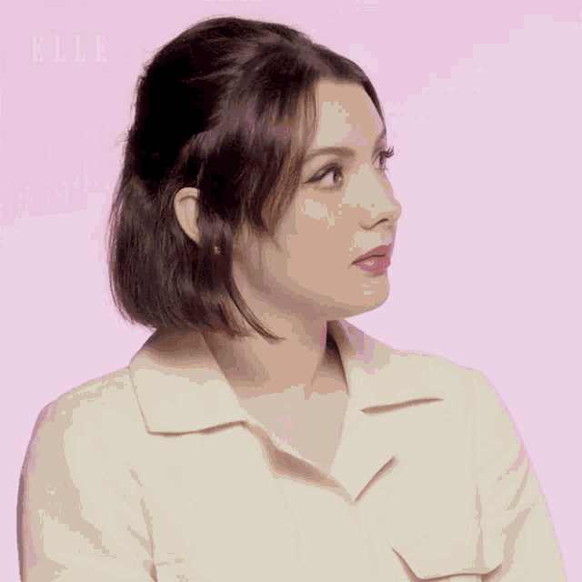 a woman 's face is shown in front of a pink background with the word elle visible