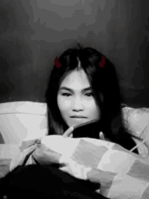 a black and white photo of a woman with red eyes and horns on her head