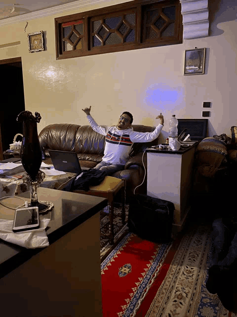 a man sitting on a couch with his arms outstretched in a living room