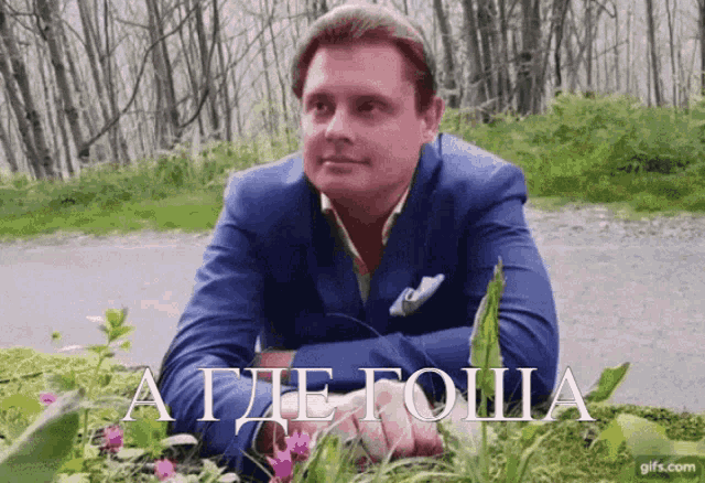a man in a blue suit is laying in the grass with a gifs.com logo in the corner