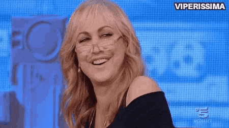 a woman wearing glasses is smiling on a television show .