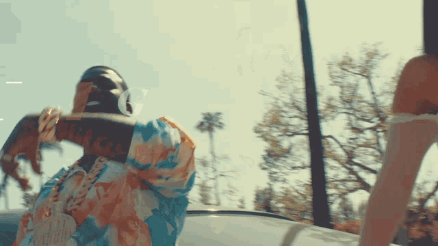 a woman in a floral dress is standing next to a man in a car