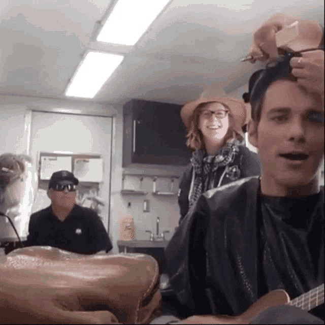 a man is getting his hair cut by a woman in a hat