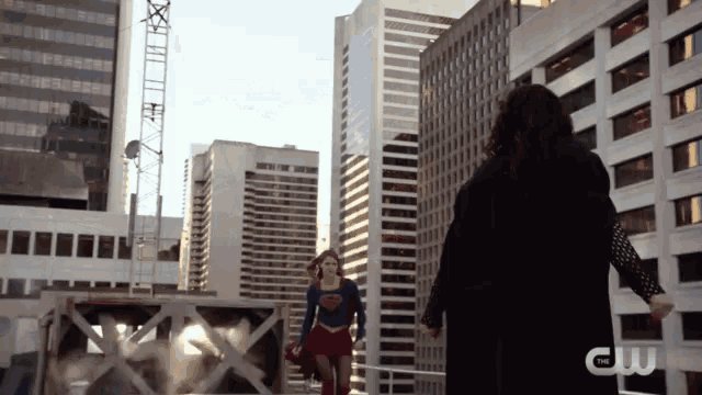 a woman in a superman costume stands next to another woman in a black coat