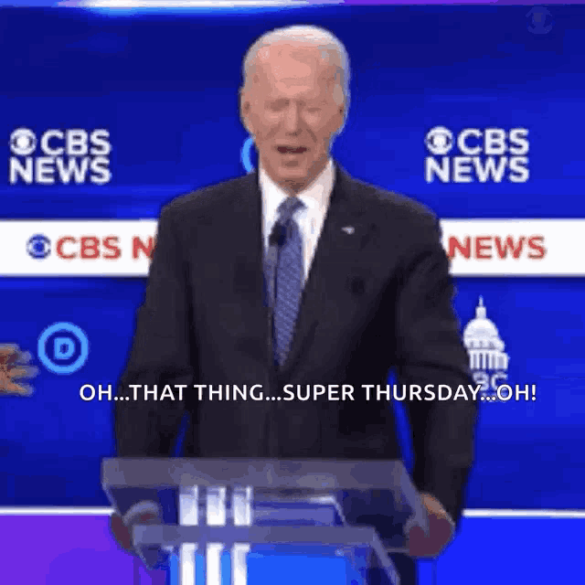 a man in a suit and tie stands behind a podium with cbs news behind him