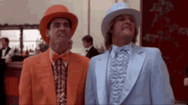 two men wearing suits and hats are standing next to each other