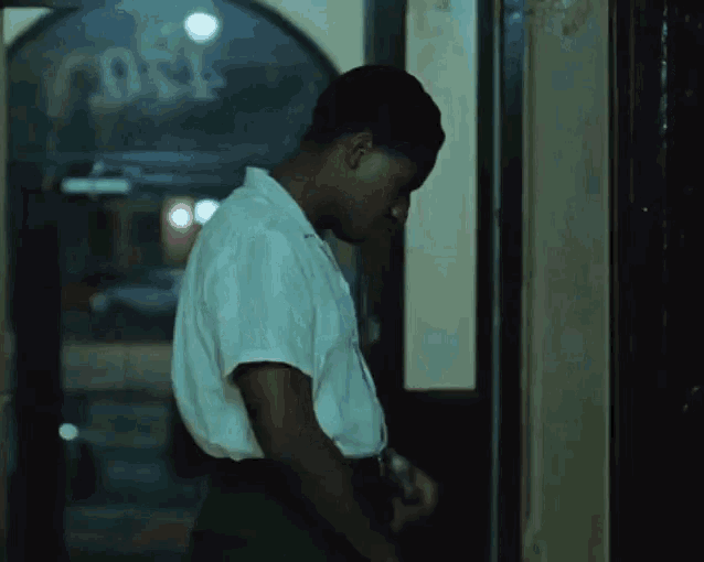 a man in a white shirt is standing in front of a door with the word close on it