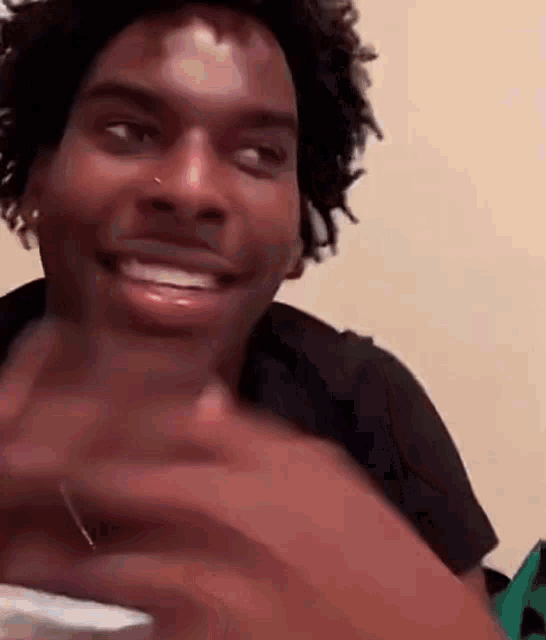 a man with dreadlocks is smiling while holding a cell phone .