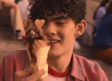 a young man with curly hair is eating ice cream