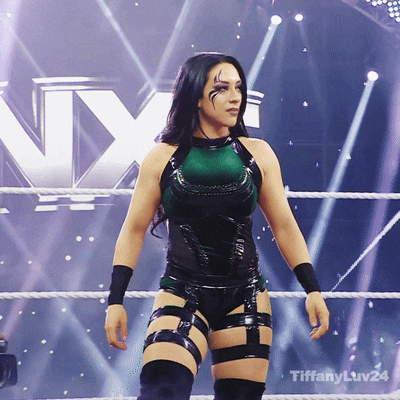 a woman in a green and black outfit is standing in a wrestling ring with tiffanyluv24 written on the bottom
