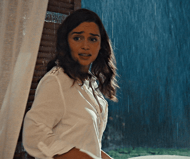 a woman in a white shirt stands in front of a window in the rain