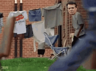 a man standing in front of a brick building with clothes hanging on a clothes line .