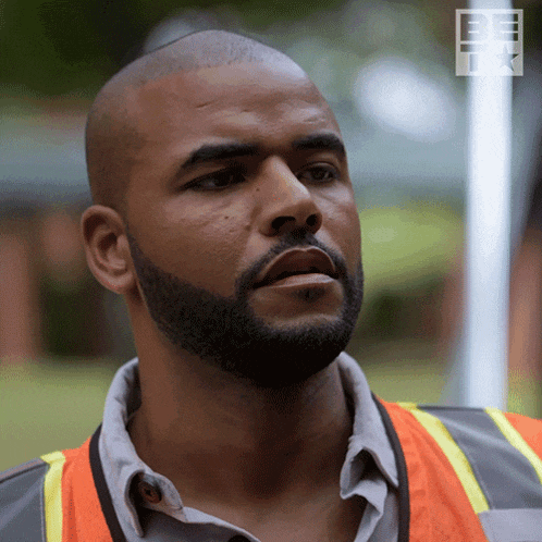 a man with a beard is wearing a safety vest with the word be on the bottom