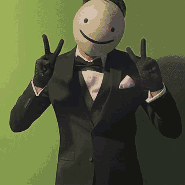 a man in a tuxedo with a smiley face mask on his head