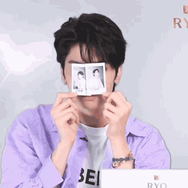 a young man in a purple shirt is holding up two pictures