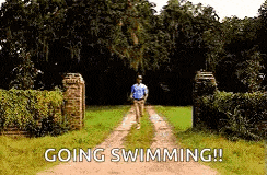 a man is running down a dirt road with the words `` going swimming '' written on the side .