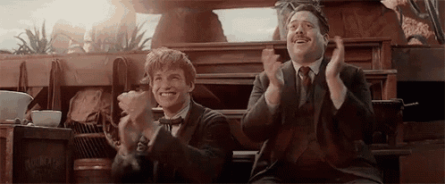 two men are sitting next to each other and clapping their hands .