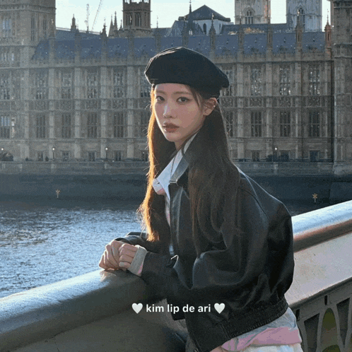 a woman wearing a beret and a leather jacket is leaning on a railing with the words kim lip de ari written below her