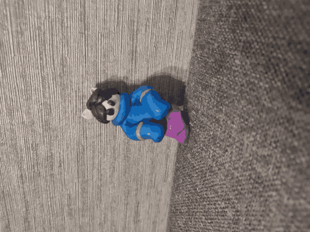 a small figurine of a person in a blue jacket is sitting on a couch