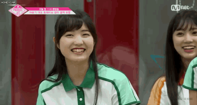 a girl in a green and white shirt is smiling next to another girl in a red shirt .