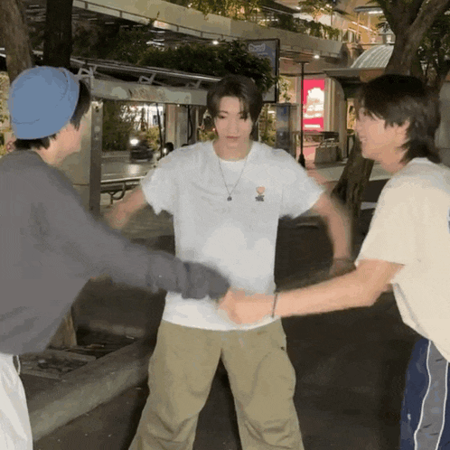 a man wearing a white t-shirt with a bear on it shakes hands with two other people