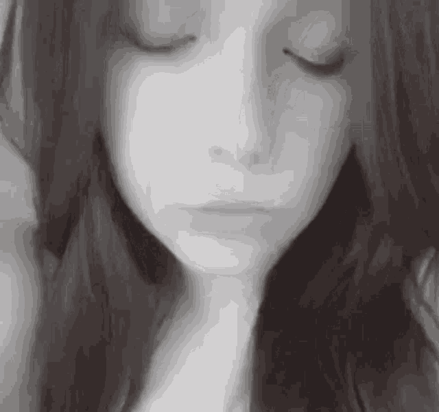 a black and white photo of a girl with her eyes closed .
