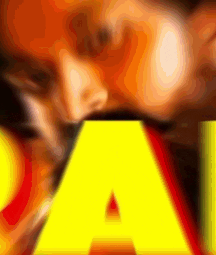 a close up of a yellow letter a with a face in the background
