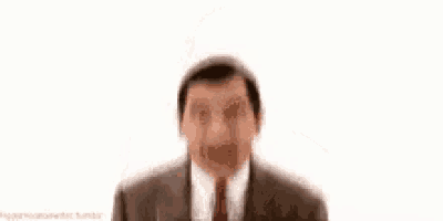 mr bean is wearing a suit and tie and is smiling .