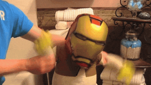 a man wearing a blue shirt with the letter r on it is washing an iron man helmet