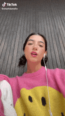 a woman wearing a pink sweater with a yellow smiley face on it .