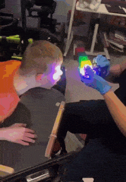 a person in a blue glove is holding a rainbow colored cube in front of a child in a wheelchair