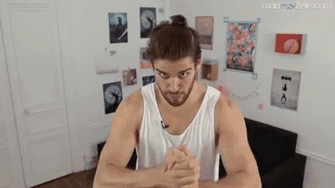 a man in a white tank top is standing in a room with a bun on his head