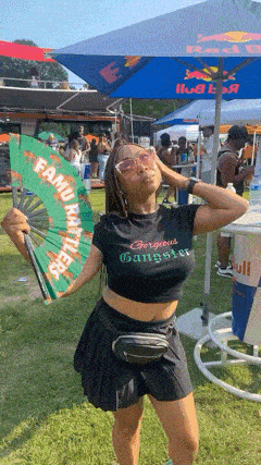 a woman holding a green fan with famous gangster written on it