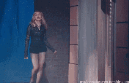 a woman in a leather jacket and shorts is walking through a hallway .