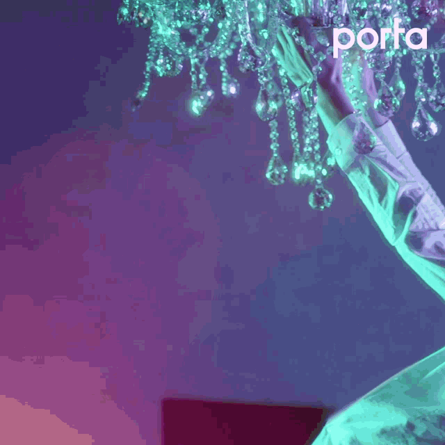 a person reaching up to a chandelier with the word porta on the bottom right
