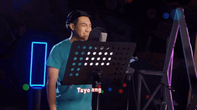 a man singing into a microphone with the words " tayo ang ligaya " above him