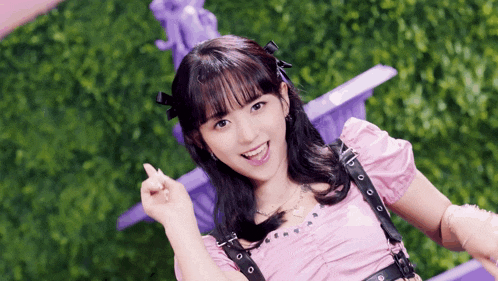 a girl in a pink top is giving a heart sign