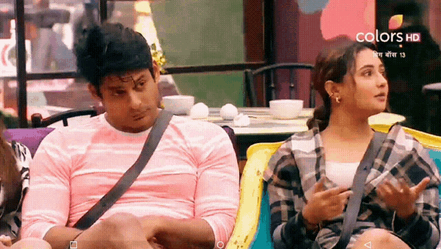 a man and a woman are sitting on a couch in front of a screen that says colors hd